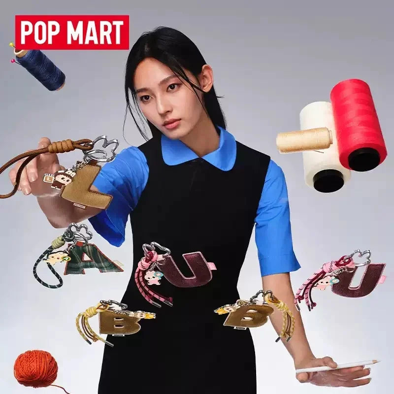 Labubu Pin for Love. Woman holding various keychains with colorful spools of thread in the background, featuring the Pop Mart brand.
