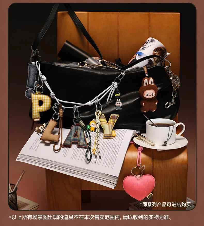 Labubu Pin for Love. Black handbag with various charms on a wooden surface with a cup of coffee and newspaper.