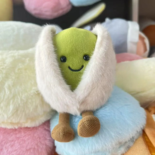 Jellycat pistachio. Plush toy resembling a green character with a white cape on a colorful background