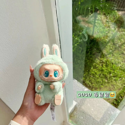 Green plush toy Labubu held in a hand with a blurred outdoor background