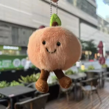 Jellycat. Plush keychain shaped like a cartoonish bread roll with a blurred outdoor background
