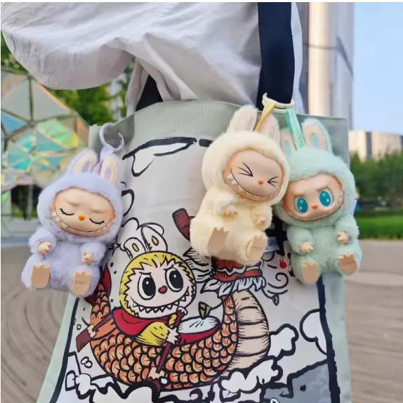Three Labubu character keychains on a bag with a colorful design.