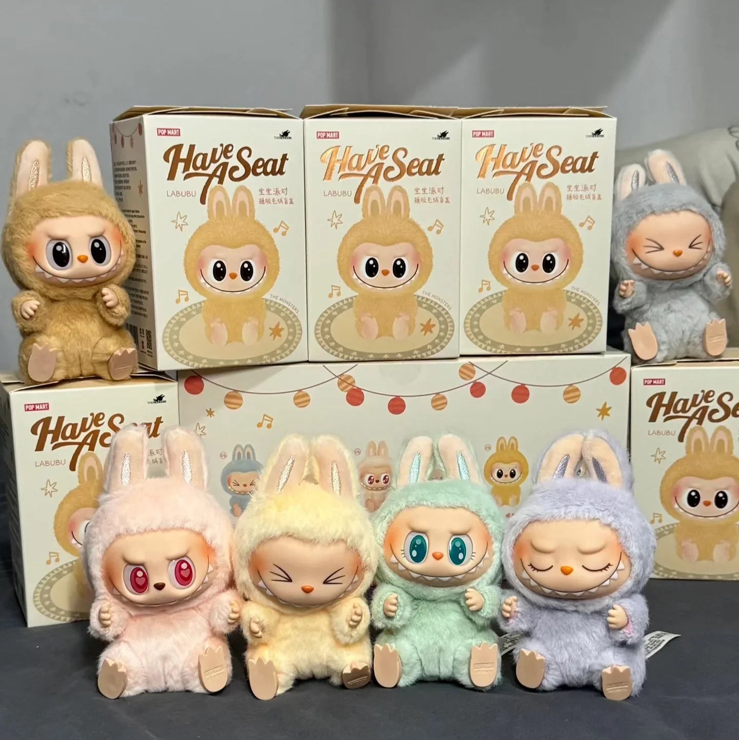 Plush toys Labubus and boxes of 'Have a Seat' on a gray background