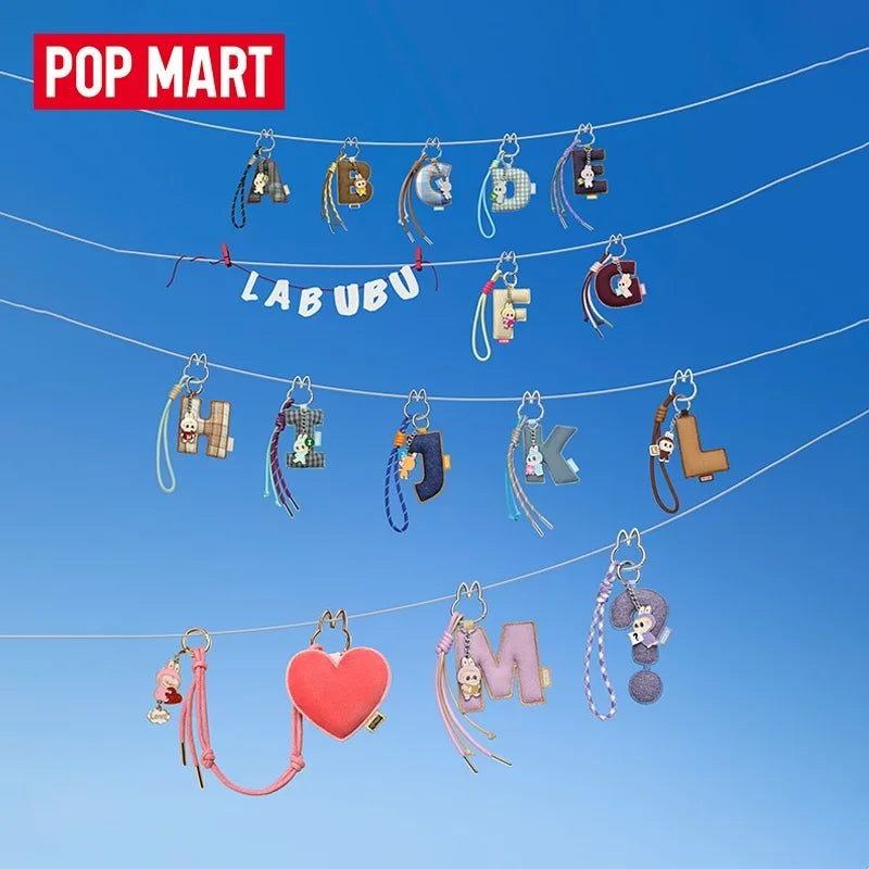 Labubu Pin for Love. Various keychains hanging on strings against a blue sky with 'Pop Mart' and 'Labubu' branding.